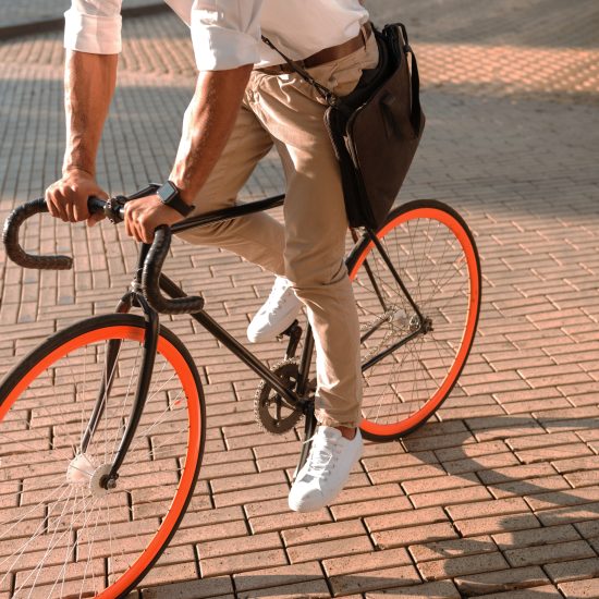 Cropped picture of young person early morning with bicycle walking outdoors.